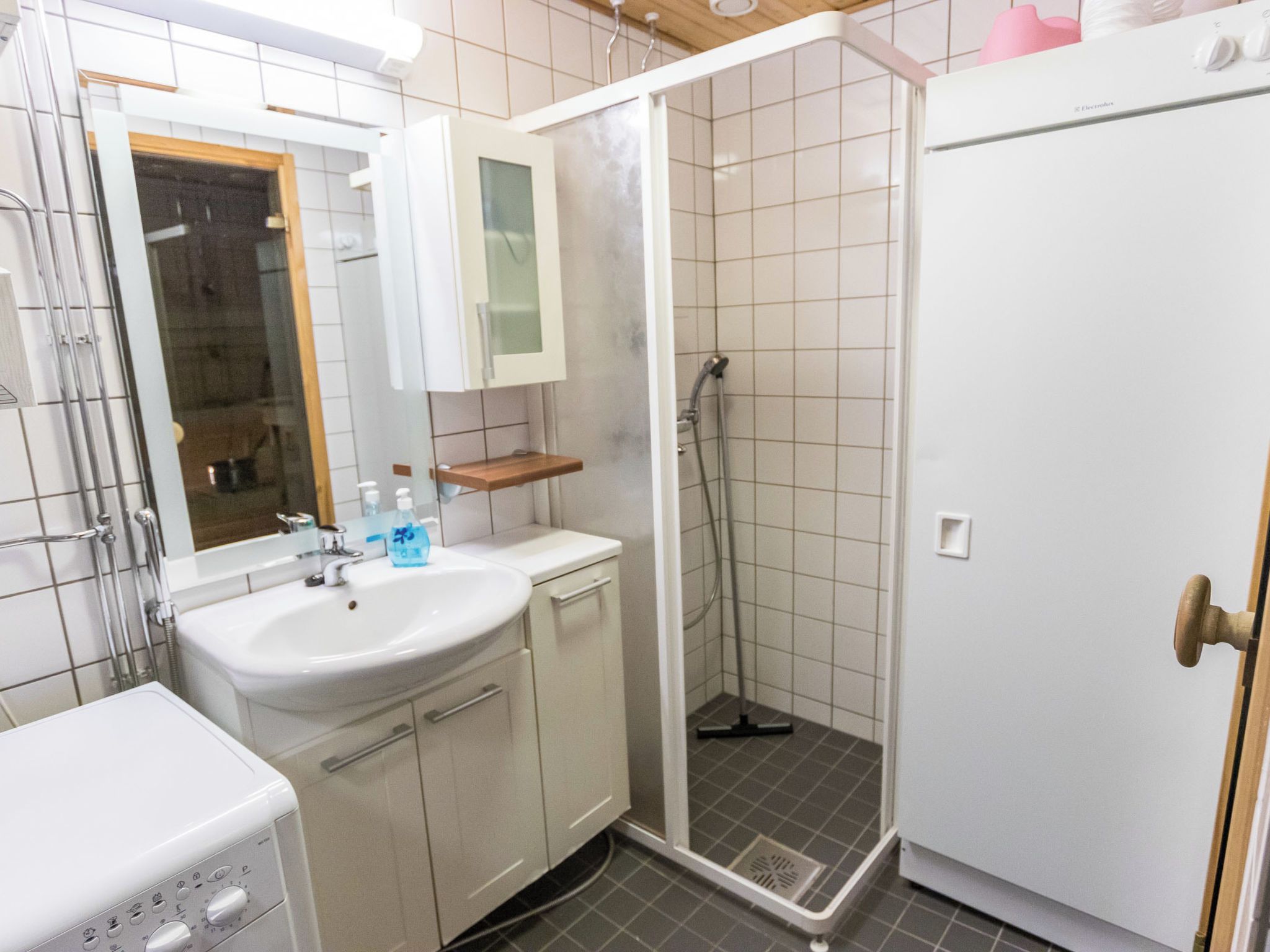 Ein Badezimmer mit einem weißen Waschbecken, einem Spiegel und einer Duschkabine.