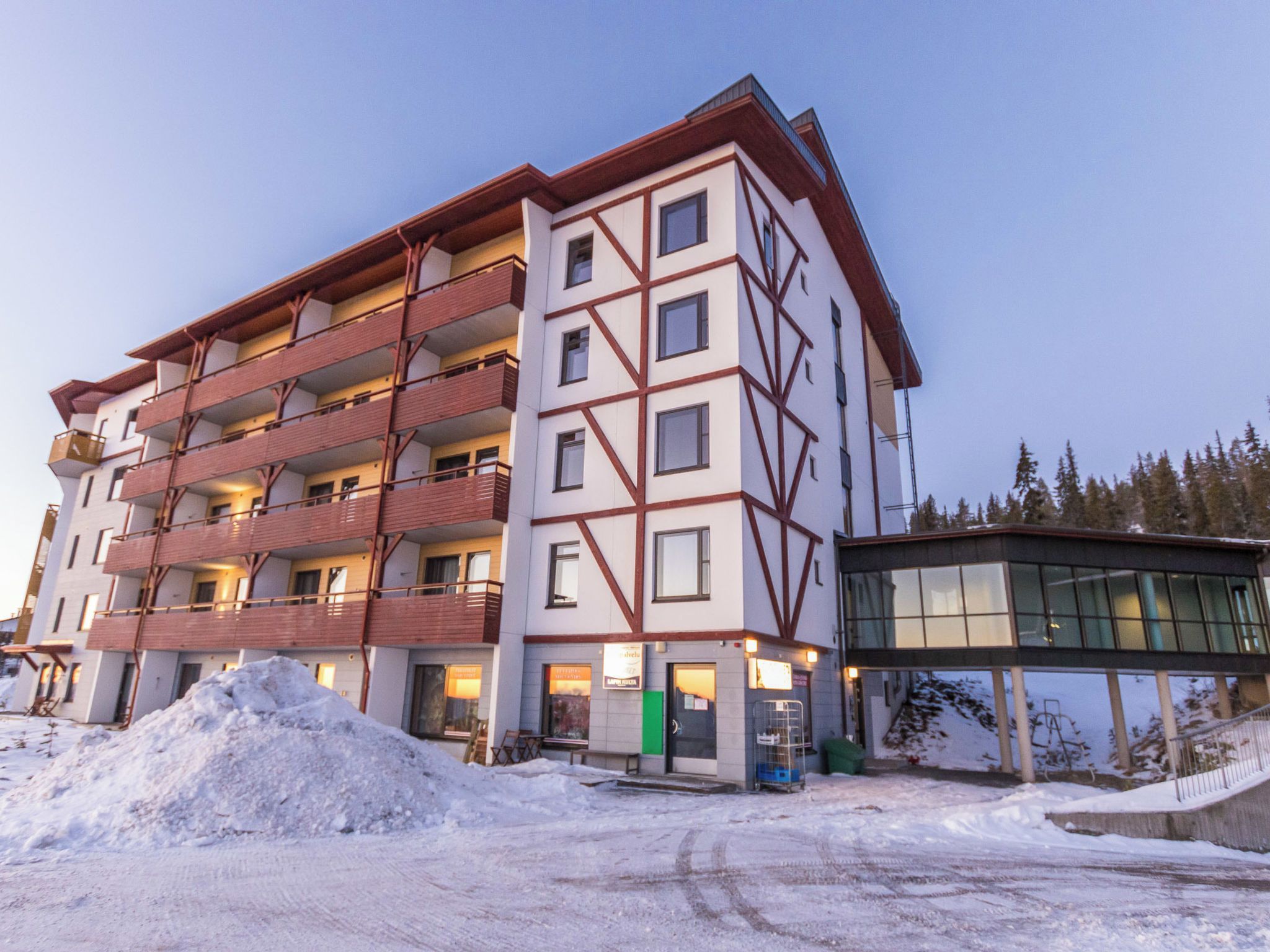 Ein mehrstöckiges Hotel mit modernem architektonischen Design, mit Balkonen und einem Skiliftbereich.