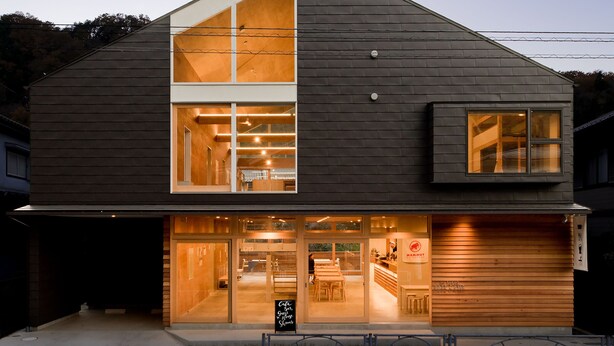 A two-story building with a large glass window on the ground floor, a wooden interior, and a sign that reads "Cafe." - Mt.Takao Base Camp - Hostel (Hachioji)