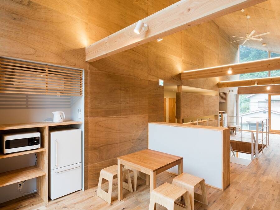 Una cocina moderna con armarios de madera, microondas, refrigerador y una mesa de comedor de madera con taburetes.