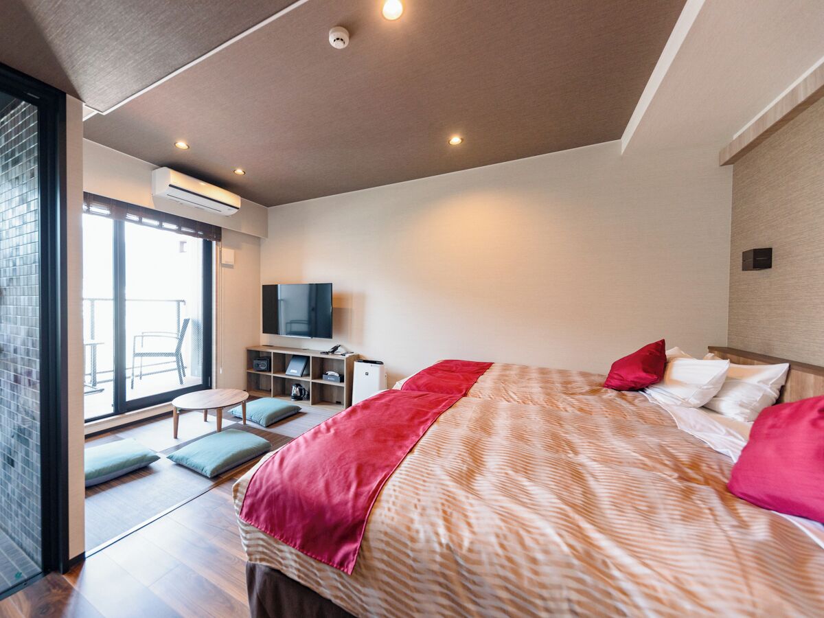 Et moderne hotelværelse med en stor seng, fjernsyn, skrivebord og balkon.