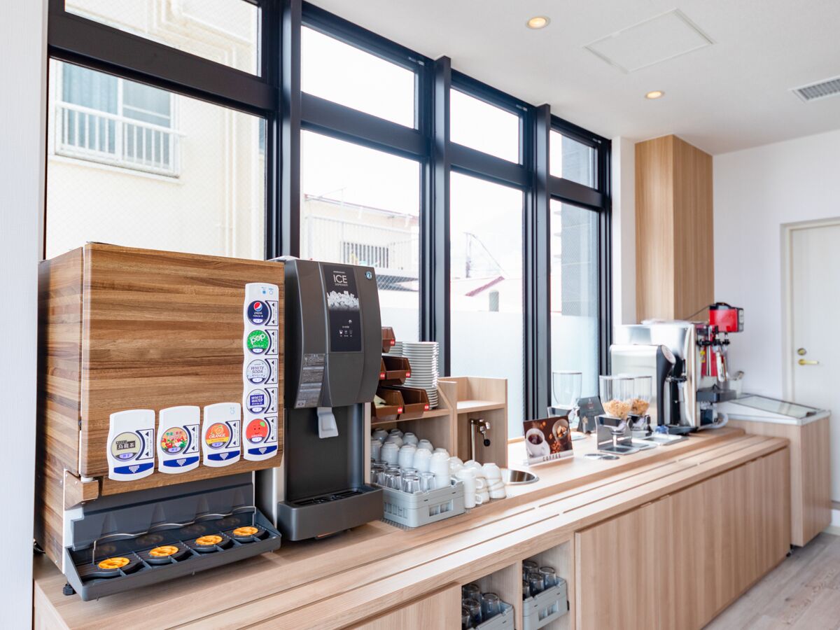 Una cafetería moderna con mostrador de madera, una máquina de café y diversas opciones de bebidas.
