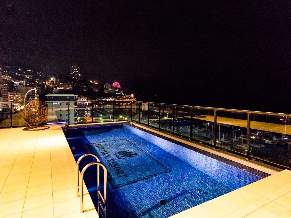 Ein Pool auf dem Dach mit Blick auf die nächtliche Stadt.