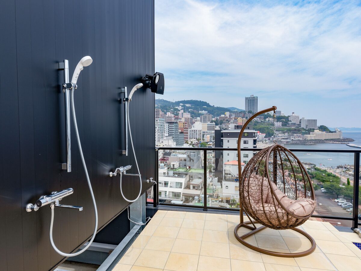 A balcony with a hanging chair, a shower, and a city view.