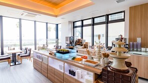 A modern kitchen with a long counter, various food items, and a decorative chocolate fountain. - LiVEMAX RESORT ATAMI SEA FRONT (Atami)