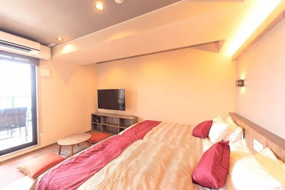 Une chambre dâhĂŽtel avec un lit, une tĂ©lĂ©vision, une petite table et une fenĂȘtre.