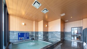 A modern indoor pool area with a large rectangular pool, wooden ceiling panels, and a blue informational sign on the wall. - LiVEMAX RESORT ATAMI SEA FRONT (Atami)
