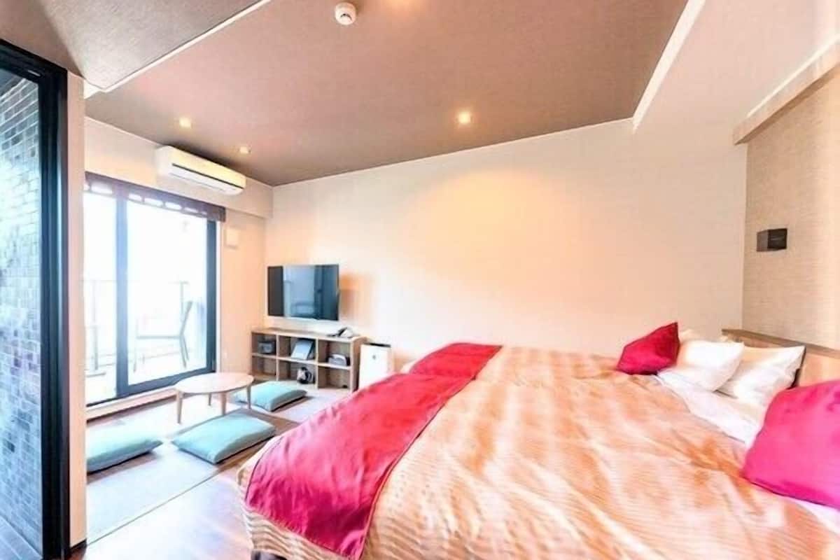 A modern hotel room with a large bed, a television, and a seating area with a view.