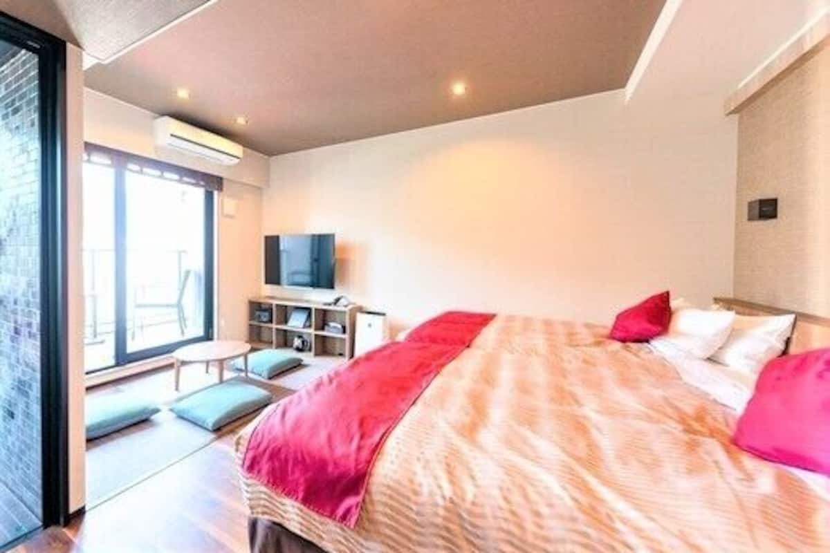 A modern hotel room with a large bed, a television, and a seating area with a view.