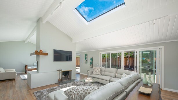 A spacious living room with a large sectional sofa, a fireplace, and a skylight. - Pebble Beach Retreat • Ocean Views • Infrared Sauna • Short Walk to Beach (Del Monte Forest)
