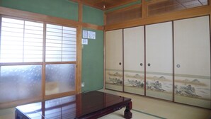 A traditional Japanese room with tatami flooring, a low wooden table, sliding shoji doors, and a view of a mountainous landscape through the windows. - Wakayama House No.10 (Wakayama)