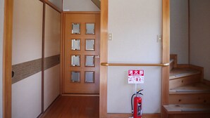 A wooden interior with a fire extinguisher mounted on the wall and a door with frosted glass panels. - Wakayama House No.10 (Wakayama)