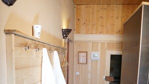 Interior de madeira com um banco, porta-toalhas e uma porta que dá para outro espaço.