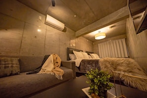 A modern bedroom with a sofa, a bed, a plant, and a lamp. - Grandouce Daikokucho (Osaka)