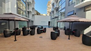 A rooftop pool area with outdoor seating and umbrellas.