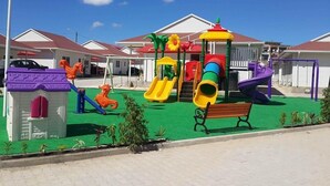 A playground with slides and swings, surrounded by buildings with red roofs. - Indico Apart Hotel (Nacala)