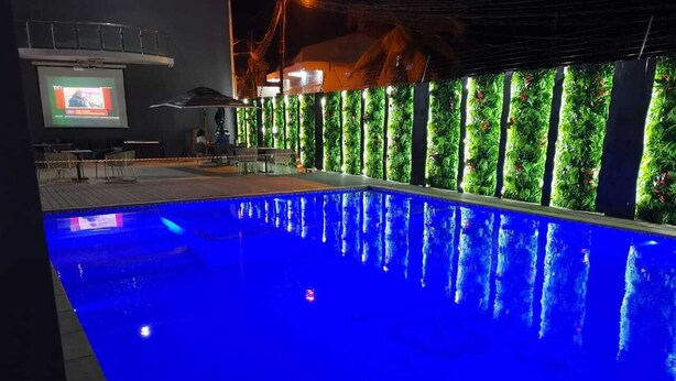 A swimming pool with blue lighting, surrounded by vertical gardens and a projection screen. - Indico Apart Hotel (Nacala)