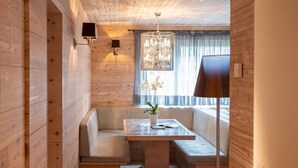 Una habitación acogedora con detalles de madera, un banco, una mesa con un florero y una araña.