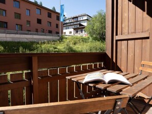 A wooden bench with an open book, set against a backdrop of buildings and greenery. - Chesa Sur Val 21 by Interhome (St. Moritz)