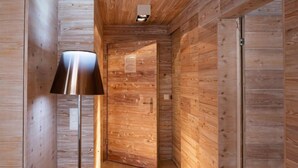 Un pasillo interior de madera con una puerta, una lámpara de pie y un accesorio de luz en el techo.