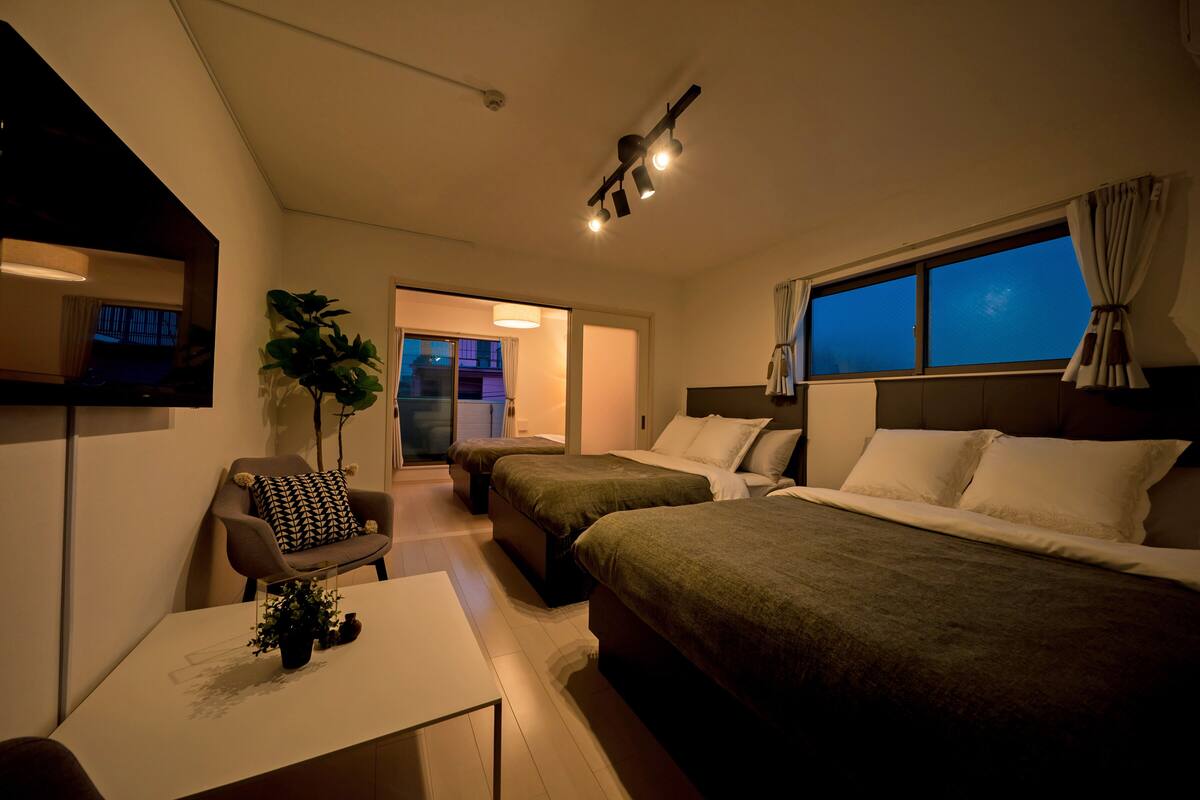A hotel room with two beds, a desk, a chair, and a TV.