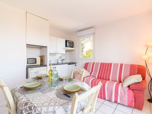 A compact living space with a dining area, kitchenette, and a sofa.