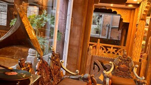 Una habitación ornamentada con un piano de cola, una mesa de madera y sillas con intrincados grabados.