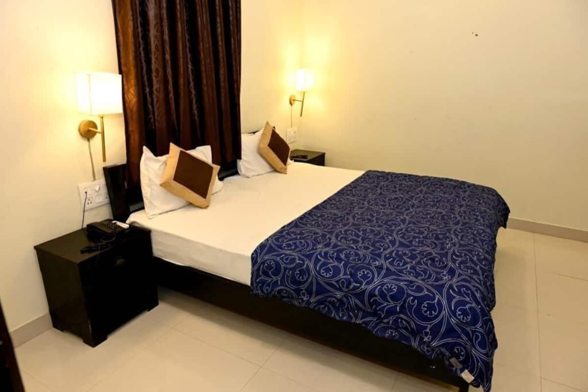 Een hotelkamer met een bed, twee nachtkastjes, een telefoon en een lamp aan beide kanten.