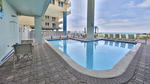 Une piscine avec une terrasse carrelée, un fauteuil de relaxation et une vue sur l’océan.