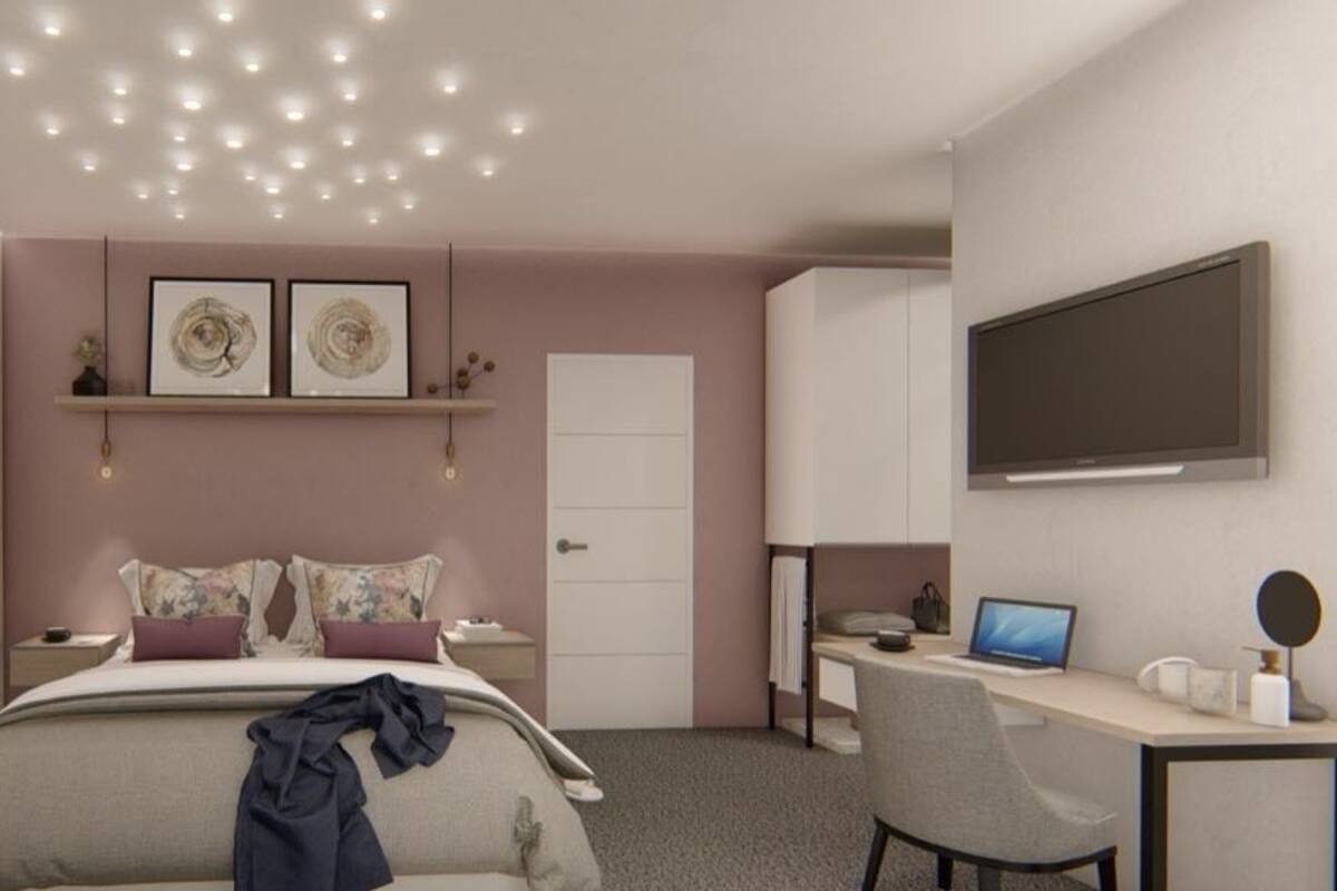 A bedroom with a bed, a desk, a chair, a TV, and a door.