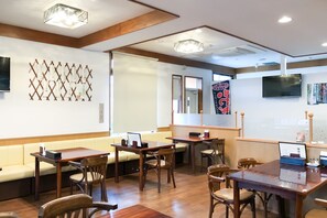 Ein modernes Interieur mit Holzmöbeln, einem Flachbildfernseher und dekorativen Wandbildern.