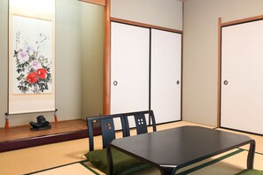 A traditional Japanese room with tatami flooring, a low table, and a painting of flowers and birds. - Hotel & Renta Car 660 Nachi - Katsuura (Nachikatsuura)