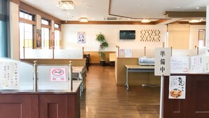 Een restaurantinterieur met houten vloeren, tafels, stoelen, een aan de muur bevestigde televisie en een rookvrij bord.