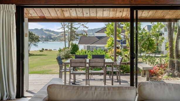 A wooden ceiling, a glass door, a view of a lake, a table with chairs, and a bench. - Sensational Sun Trap on Estuary Frontage - Pauanui (Pauanui)