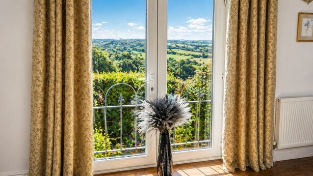 A room with a large window, a potted plant, and a radiator. - Juliet Cottage (Stratford-upon-Avon)