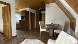 Ein gemütliches Schlafzimmer im Loft-Stil mit Holzbalkendecke, einer Couch mit flauschigen weißen Kissen und einem Essbereich im Hintergrund.