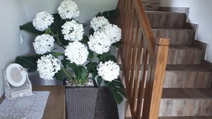 Eine Treppe mit hölzernen Geländern und einem weißen Hortensienstrauch am Fuß.