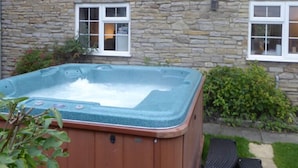 A hot tub in front of a stone building with two windows. - Macbeth Cottage (Stratford-upon-Avon)