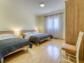 Una habitación con dos camas, una silla y un armario de madera.