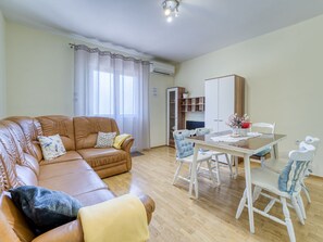 Una sala de estar con un sofá de cuero marrón, una mesa de comedor con sillas y una cocina al fondo.