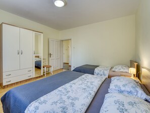 A bedroom with a bed, bedside table, lamp, wardrobe, and a chair.