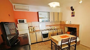 A compact kitchen with a dining area, a TV on a stand, and a fireplace. - Apartment Dijana by Interhome (Korcula/Prigradica)