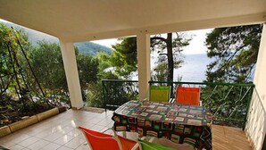 A covered patio with a table and chairs, overlooking a mountainous landscape and the sea. - Apartment Dijana by Interhome (Korcula/Prigradica)