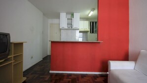 A room with a kitchenette, a television on a wooden stand, and a white sofa. - Gohouse - Baependi 503 (Rio de Janeiro)