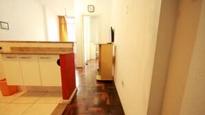 A hallway with a kitchen area on the left, a wooden floor, and a door at the end. - Gohouse - Baependi 503 (Rio de Janeiro)