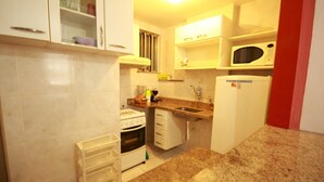 A compact kitchen with white cabinets, a microwave, a stove, and a sink. - Gohouse - Baependi 503 (Rio de Janeiro)