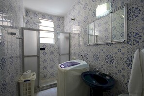A bathroom with a shower, toilet, and sink, featuring blue and white patterned tiles.