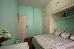 A bedroom with a bed, a wardrobe, and a door.