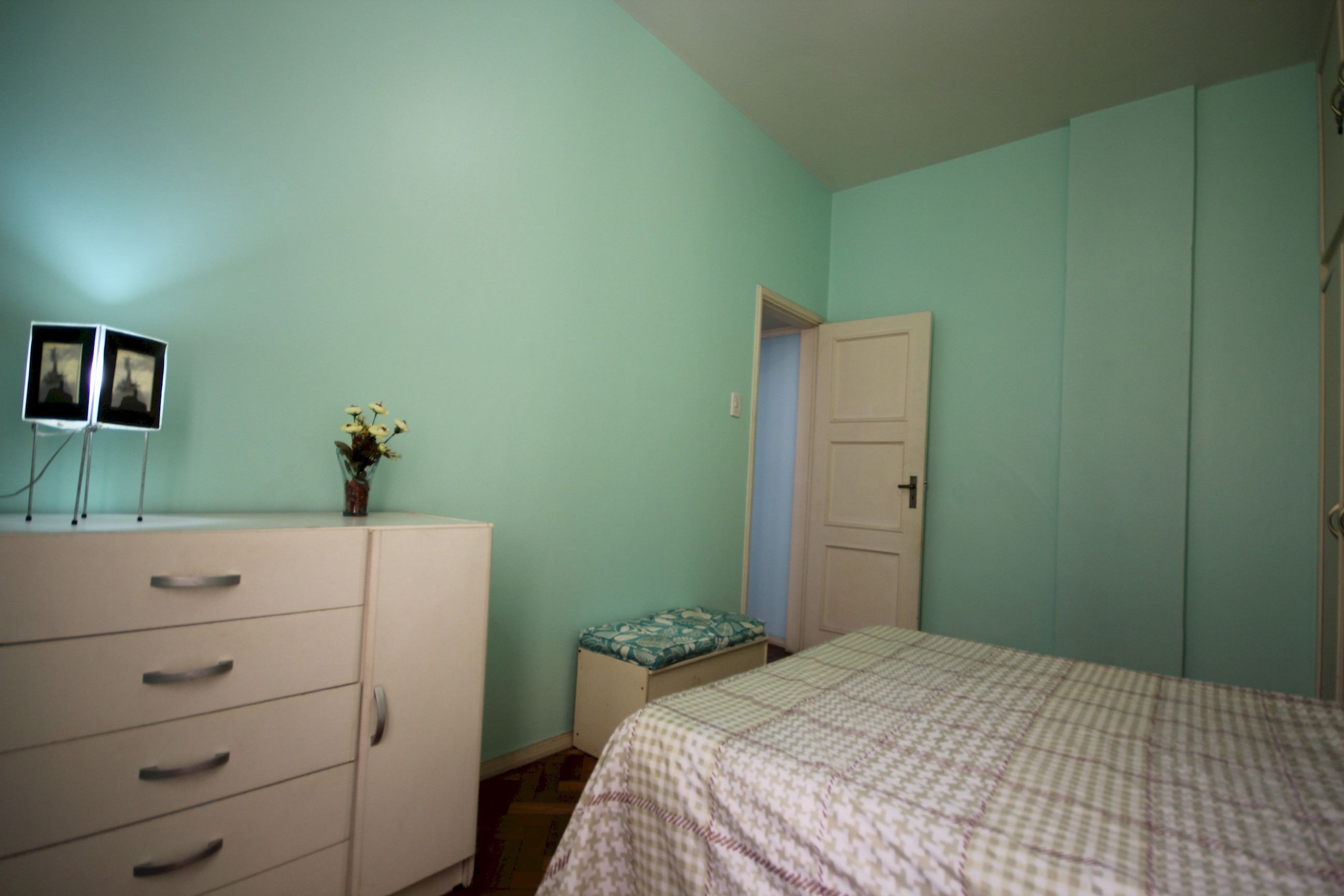 Un dormitorio con una cama, un aparador y una puerta que da a otra habitación.