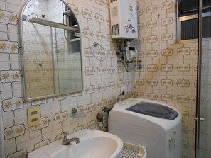 A bathroom with a white sink, mirror, and a white water heater mounted on the wall.